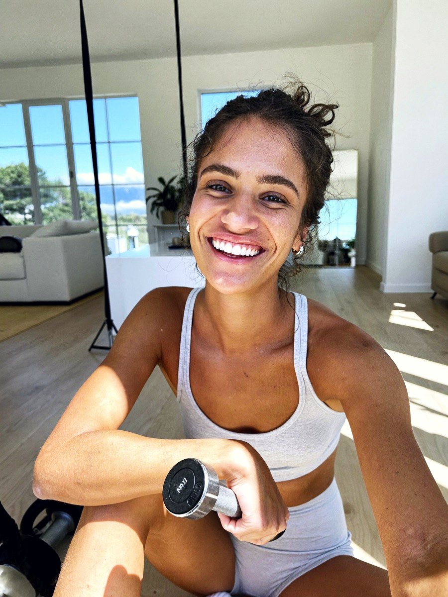 A woman resting between sets in a bright home studio, smiling